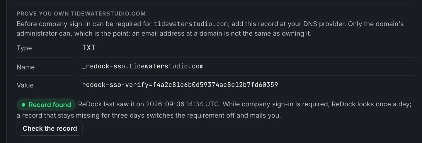 The Prove you own your domain panel: a TXT record with its name and value, marked Record found with the time ReDock last saw it, a note saying ReDock looks once a day while company sign-in is required and that a record missing for three days switches the requirement off and mails you, and a Check the record button.